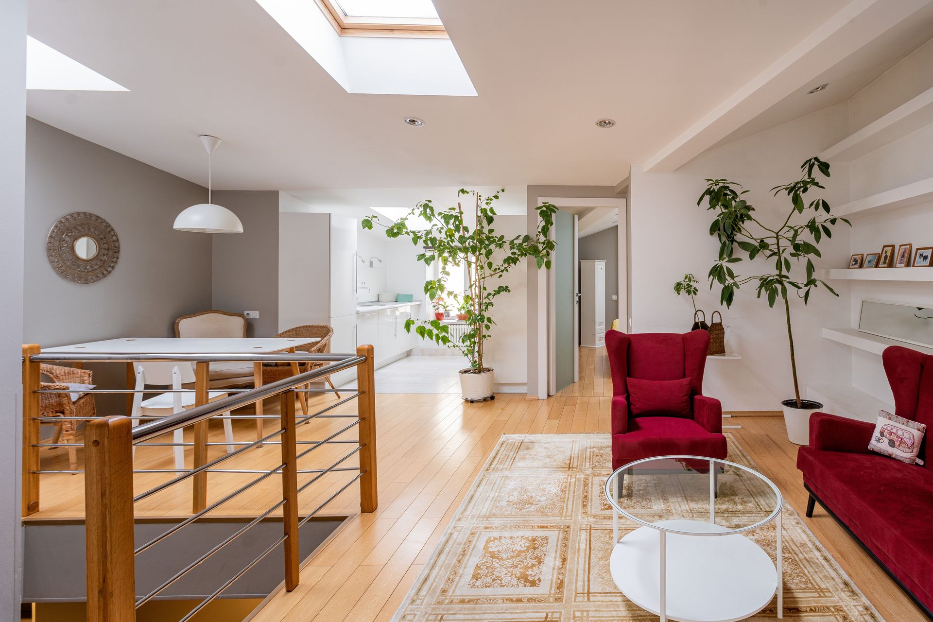 A bright, contemporary living room featuring red armchairs and minimalist design elements.